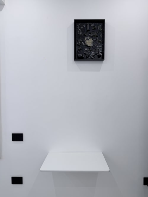 Installazione d'arte contemporanea nella camera d'albergo Sabò Bologna, opera astratta in cornice nera sopra scaffale bianco