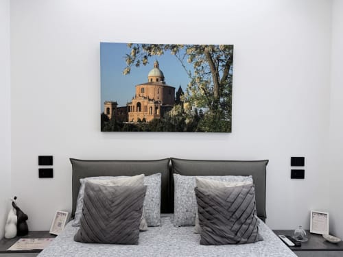 Camera elegante di Sabò Bologna con letto rivestito in grigio, cuscini decorativi e opera raffigurante basilica