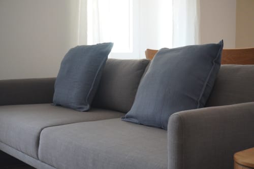 Sofá tapizado gris con cojines azules en el estudio Palacio Mambrilla, Valladolid