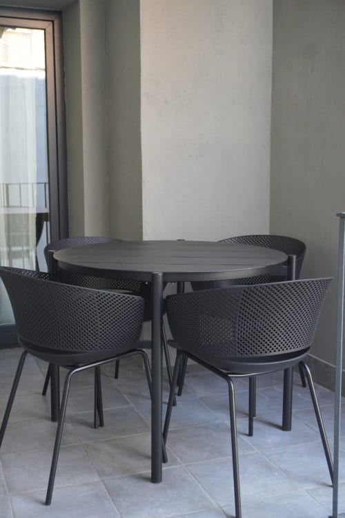 Comedor moderno con mesa redonda negra y sillas perforadas en el apartamento Palacio Mambrilla de Valladolid, con vistas a la ciudad