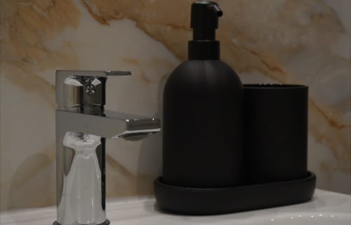 Modernas amenidades de baño en el apartamento de lujo Palacio Mambrilla en Valladolid, con grifo cromado y dispensador negro
