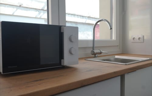 Moderna encimera de cocina con microondas, fregadero y ventanas en el apartamento Palacio Mambrilla, Valladolid