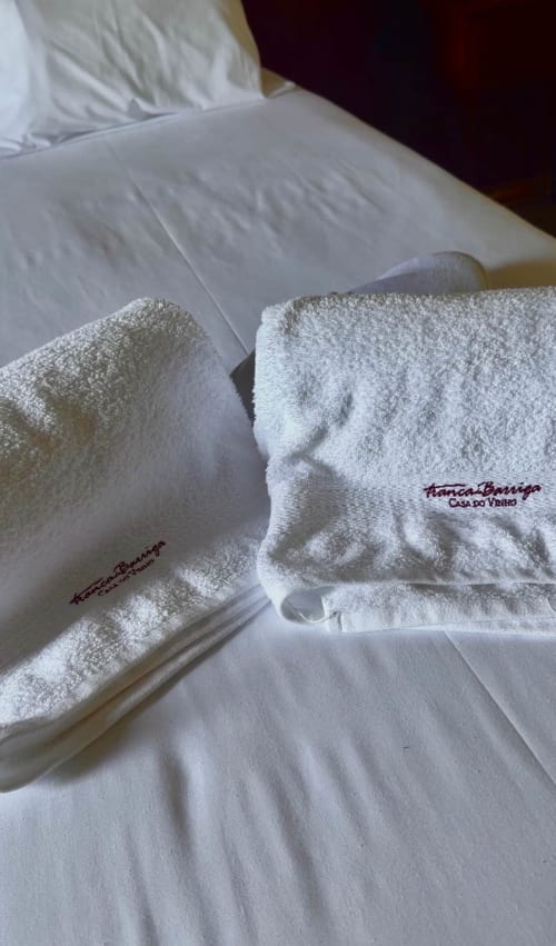 Toalhas brancas com marca Tranca da Barriga em roupa de cama impecável nesta quinta de hóspedes portuguesa
