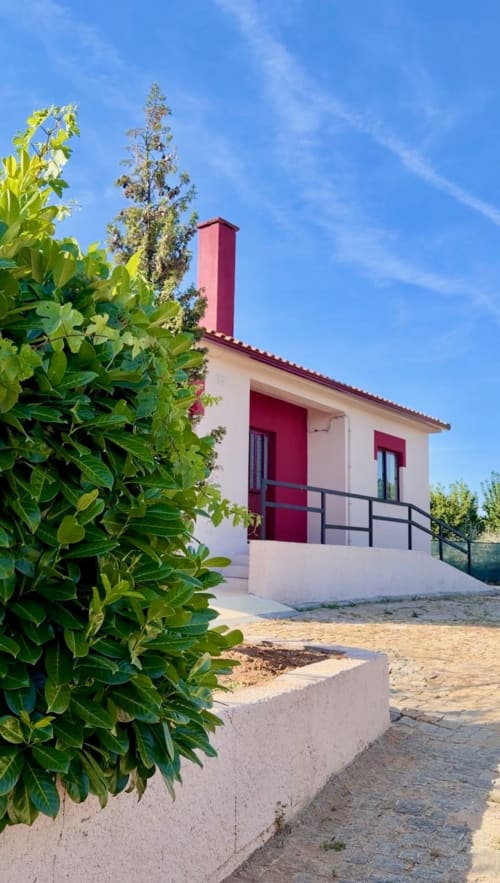 Casa rural Tranca da Barriga em Dominguiso com detalhes em vermelho e vistas para a montanha, rodeada de vegetação exuberante