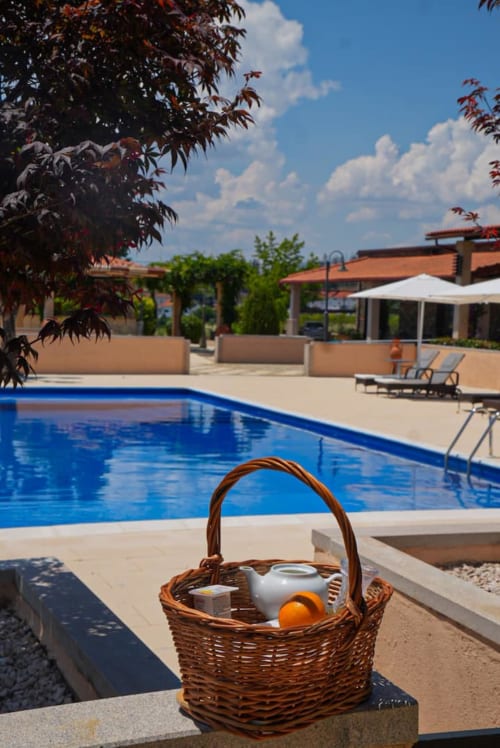 Cesto de vime com bebidas à beira da piscina da Tranca da Barriga Casa do Vinho, chalé de montanha português