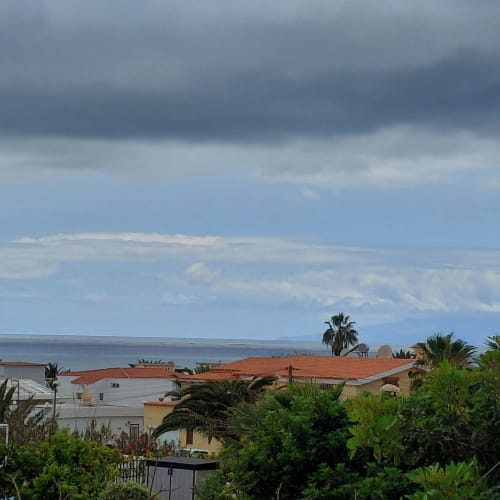 Vista al mar desde el bungalow My Little Bungalow.Com en El Palm-Mar con casas mediterráneas y palmeras