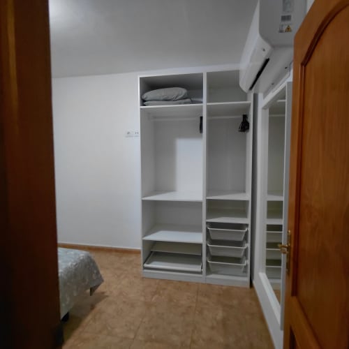 Armario empotrado blanco con estantes y cajones en la habitación del alojamiento El Palm-Mar