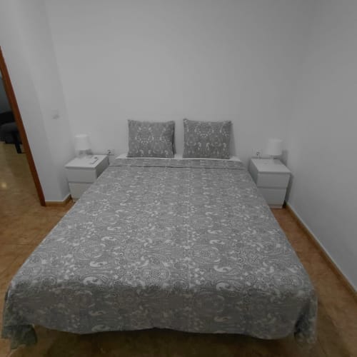 Dormitorio moderno en la casita My Little Bungalow, El Palm-Mar, con ropa de cama gris estampada y mesillas blancas