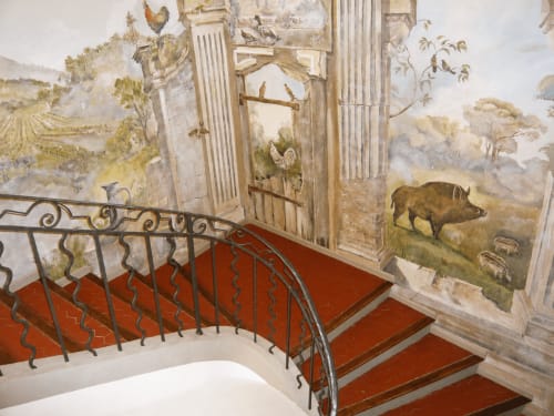 Grand escalier aux marches rouges et rampes en fer forgé à l'Auberge du Parc, avec murs ornés de fresques classiques