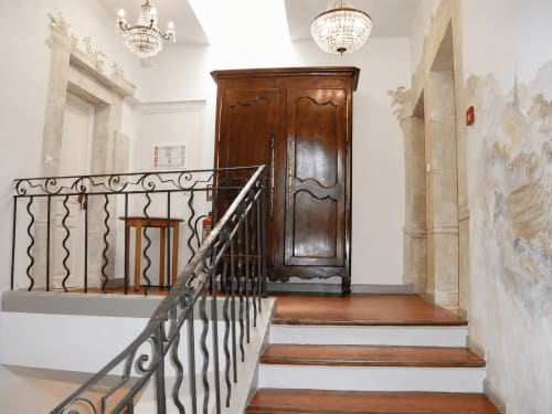 Grand escalier avec rampe en fer forgé menant à une armoire en bois dans le hall d'entrée de l'Auberge du Parc