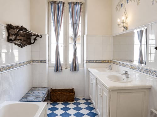 Salle de bain élégante à l'Auberge du Parc avec vasques doubles, carrelage damier bleu et blanc, rideaux à rayures