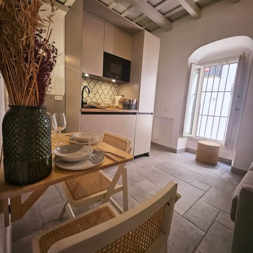 Modern open-plan kitchen and dining area at Casa De La Cruz Vejer, Cádiz with cream cabinetry and wooden table seating