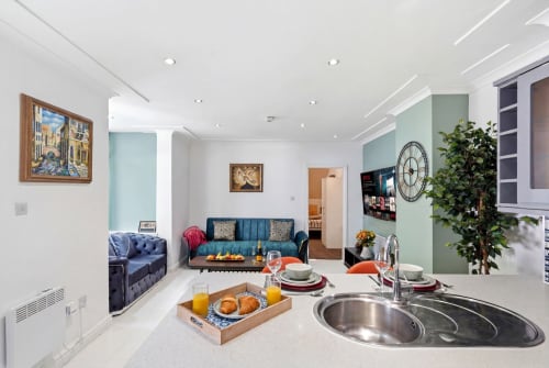 Modern Birmingham apartment kitchen and living area with blue sofa, dining setup, and sage green accents at 11.11 Property