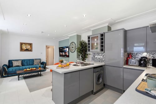 Modern gray kitchen with island sink, open-plan living area, blue sofa, Birmingham apartment