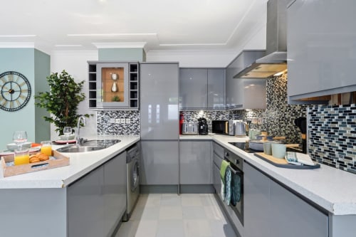 Modern gray kitchen at 11.11 Property Estates Birmingham apartment with mosaic backsplash and white countertops