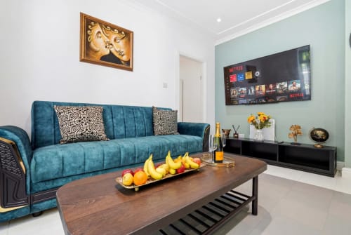 Modern apartment living room at St Augustine's Place Birmingham with teal sofa, wooden coffee table, and wall-mounted TV