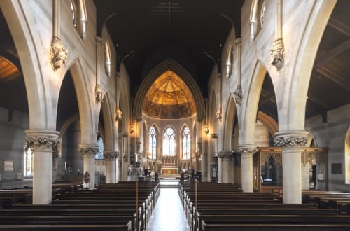 Historic St Augustine's Church interior, Birmingham, featuring soaring white columns, stained glass windows, and ornate
