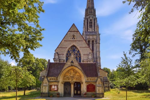 Gothic Revival chapel with tall spire surrounded by trees at St Augustine's Place, Birmingham