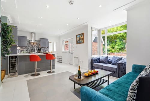 Modern apartment at 11.11 Property Estates Birmingham featuring open-plan living with teal seating, kitchen island with red