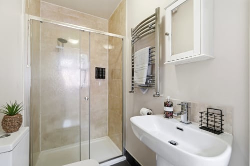 Modern bathroom at St Augustine Place, Birmingham with walk-in shower, heated towel rail, and white basin sink
