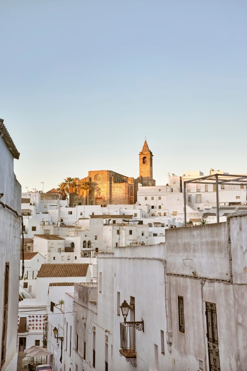 White-walled Andalusian village of Vejer de la Frontera with golden-lit church tower, Casa De La Cruz hotel location