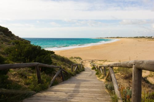 Wooden boardwalk leading to pristine sandy beach with turquoise waters near Vejer de la Frontera, Cádiz