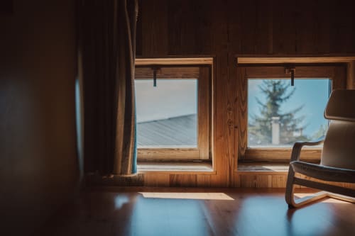 Chambre alpine ensoleillée à L'Alp'In, La Plagne : fenêtres en bois, chaise et parquets avec vue sur les montagnes.