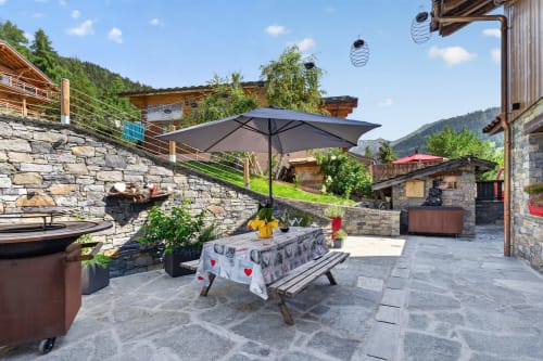 La terrasse L'Alp'In avec parasols, vue sur les montagnes et architecture alpine en pierre à La Plagne Tarentaise