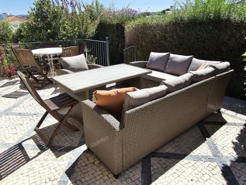 Spacious garden patio with rattan sofa, dining table, and lounge seating at Casa Oleias villa in Sesimbra