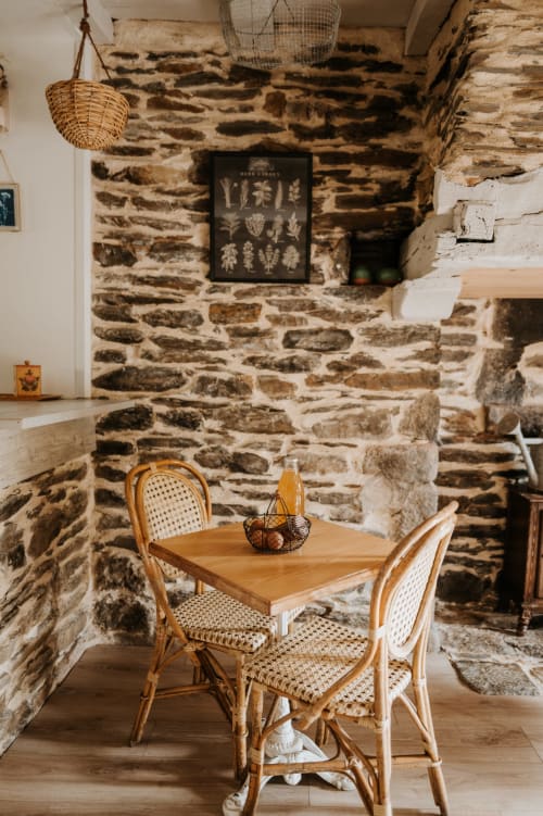 Salle à manger rustique aux Granges de Pil Bara avec table en bois, chaises en rotin et décor botanique à Langoat