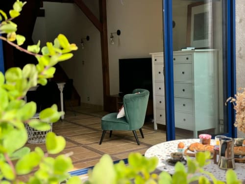 Fauteuil en velours vert dans la chambre moderne de La Maison sous les Vignes, gîte français au décor contemporain