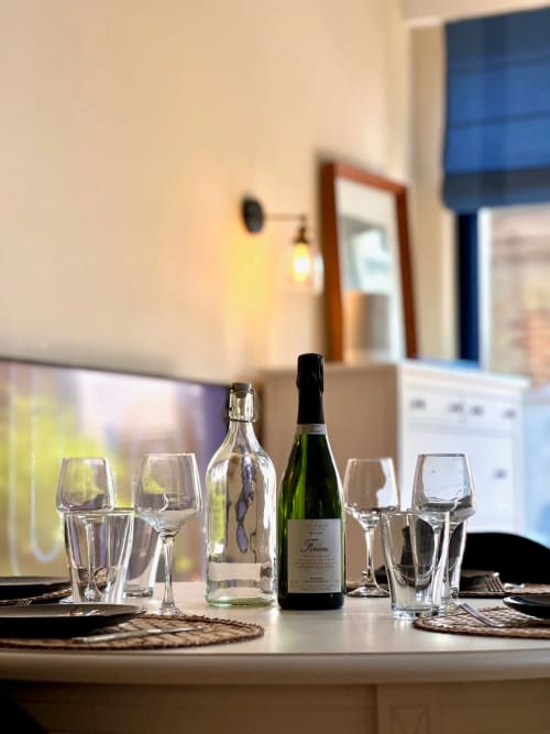 Table élégante dressée à La Maison sous les Vignes avec bouteilles de vin, verres et couverts dans un vignoble français