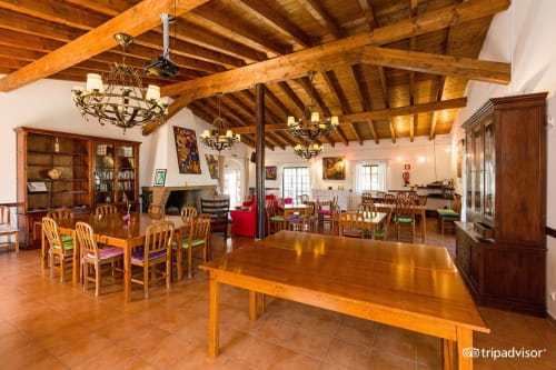 Espaçoso refeitório rústico com vigas de madeira, mesas e lareira na Herdade da Côrte, Tavira, Portugal