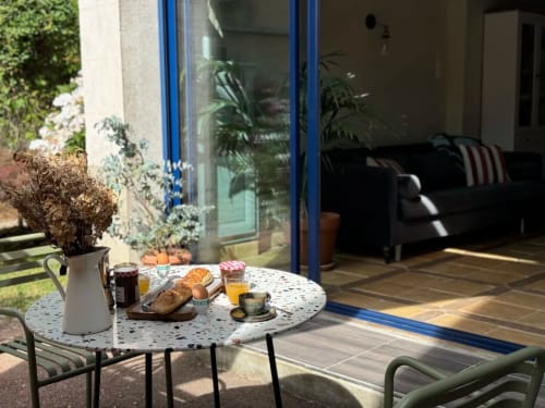 Petit-déjeuner en terrasse à La Maison sous les Vignes, gîte français avec table, viennoiseries et portes vitrées ouvertes