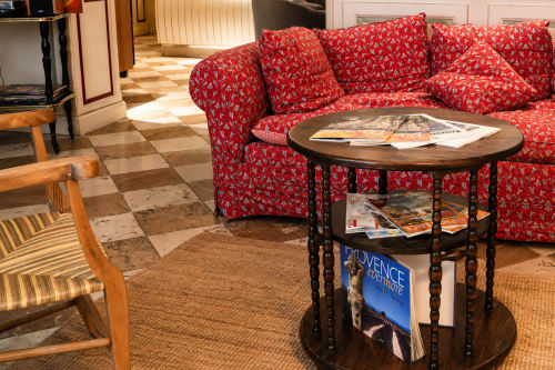 Canapé motifs rouges et table d'appoint bois dans le salon du hall de l'Auberge du Parc à Correns, France