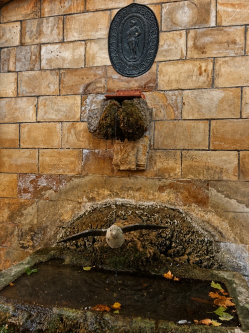 Fontaine ancienne en pierre avec plaque ornementale à l'Auberge du Parc à Correns, France