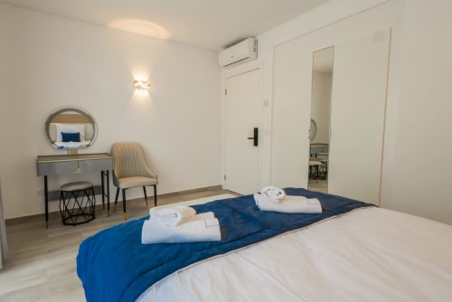 Modern bedroom at J Home Amadora with blue bedding, vanity desk, mirror, and air conditioning unit in Lisboa