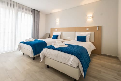 Modern twin bedroom at J Home Amadora with two beds, blue accents, wooden headboard, and contemporary furnishings in Lisboa