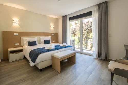 Modern bedroom at J Home Amadora with queen bed, balcony overlooking park, hardwood flooring, and contemporary furnishings in