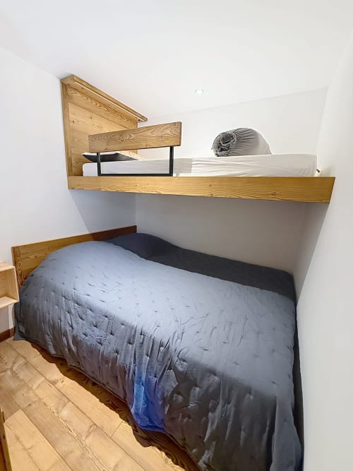 Chambre mansardée avec lit mezzanine en bois et lit bas à l'appartement Les Tanières de Montgenèvre, murs blancs et boiseries