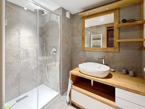 Salle de bain moderne aux Tanières de Montgenèvre avec vasque blanche, meuble en bois, grand miroir et douche à l'italienne