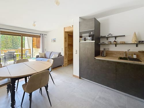 Cuisine ouverte et salle à manger moderne aux Tanières de Montgenèvre avec mobilier sombre, table en bois et