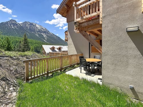 Terrasse avec vue sur les montagnes aux Tanières de Montgenèvre, balustrade en bois, coin repas et sommets alpins
