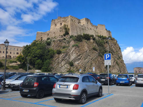 Parcheggio della B&B Pellicano Guest House con le rovine del castello storico sulla collina a Reggio Calabria, Italia