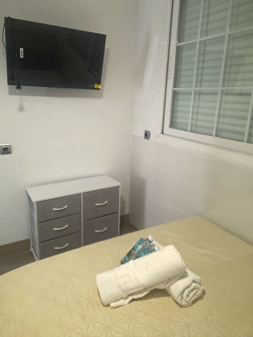 Habitación de albergue en Suki House con cama, TV de pared, unidad de almacenamiento y ventana en Pozuelo de Alarcón