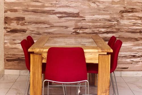 Salle à manger moderne de l'Hôtel Yakro avec table en bois, chaises en velours rouge et mur de briques rustique à Yamoussoukro