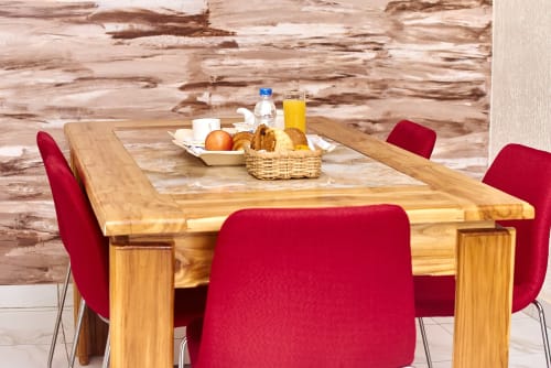 Salle à manger de l'Hôtel Yakro avec table en bois, chaises rouges et petit-déjeuner à Yamoussoukro