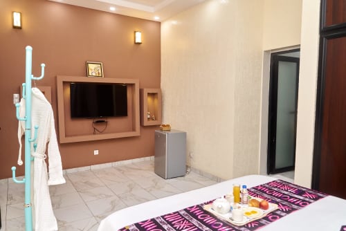 Chambre moderne à l'Hôtel Yakro à Yamoussoukro avec TV écran plat, mur d'accent terre cuite et design contemporain