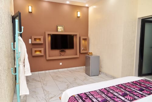 Chambre moderne à l'Hôtel Yakro à Yamoussoukro avec mur d'accent en terre cuite, télévision écran plat et sols en marbre