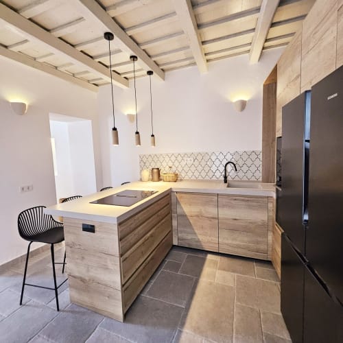 Cocina moderna en apartamento Casa De La Cruz Vejer con muebles de madera, encimeras blancas, lámparas colgantes y azulejos marroquíes